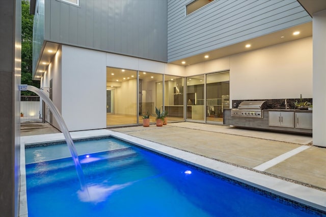 view of pool with pool water feature, an outdoor kitchen, area for grilling, and a patio