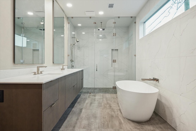 bathroom featuring separate shower and tub, vanity, and tile walls