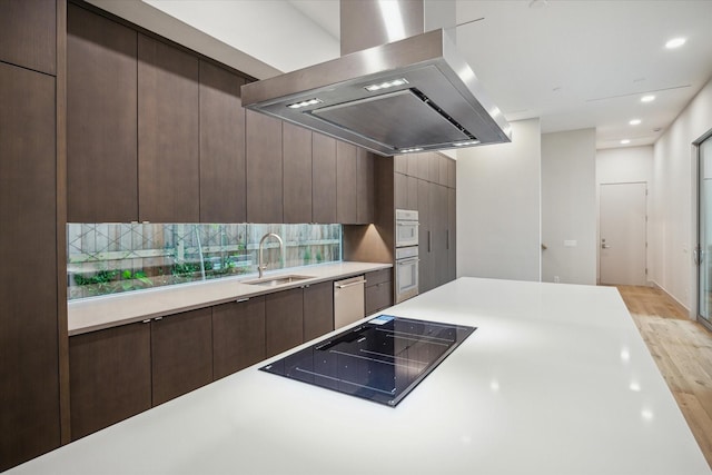 kitchen featuring dark brown cabinetry, sink, stainless steel dishwasher, island exhaust hood, and black electric cooktop