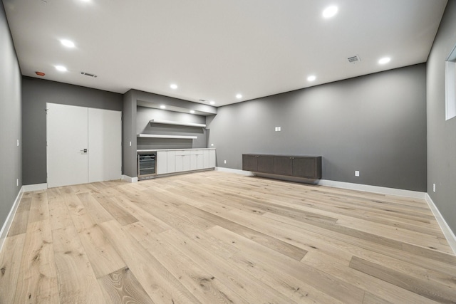 unfurnished living room with wine cooler and light hardwood / wood-style flooring