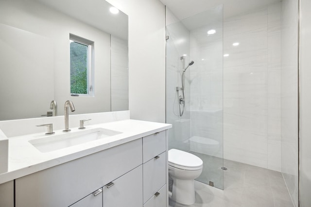 bathroom featuring a tile shower, vanity, and toilet