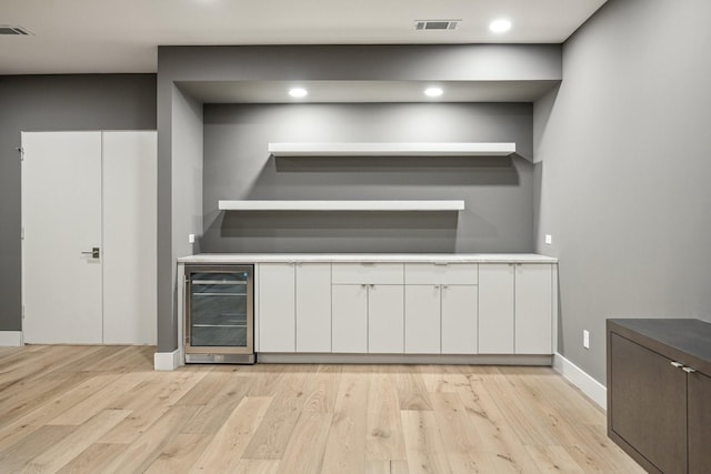 kitchen with white cabinets, light wood-type flooring, and wine cooler