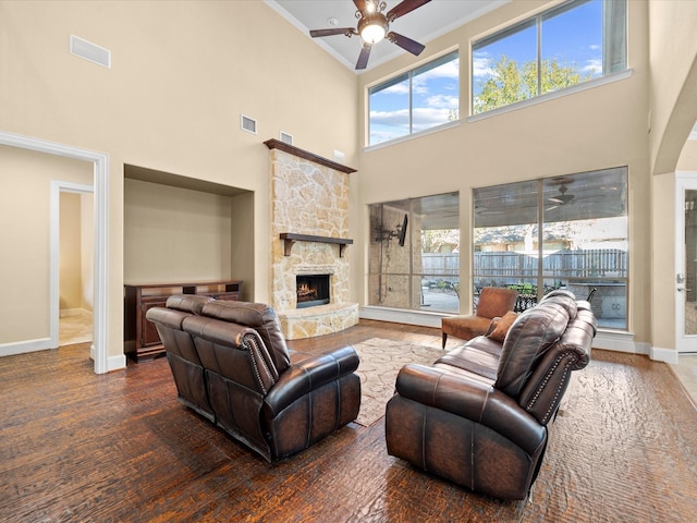 living room with a towering ceiling, a fireplace, dark wood-type flooring, and ceiling fan