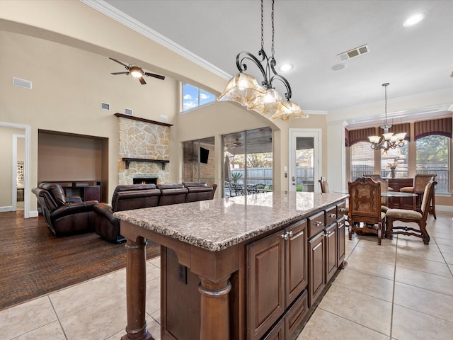 kitchen with a center island, decorative light fixtures, light tile patterned floors, ceiling fan with notable chandelier, and a fireplace