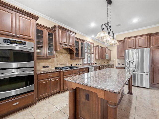 kitchen featuring stainless steel appliances, a center island, light stone counters, hanging light fixtures, and crown molding