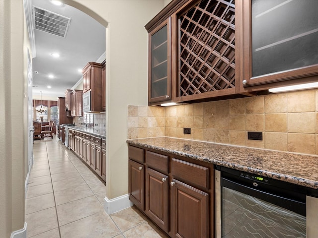 kitchen with light tile patterned floors, dark stone countertops, decorative backsplash, wine cooler, and ornamental molding