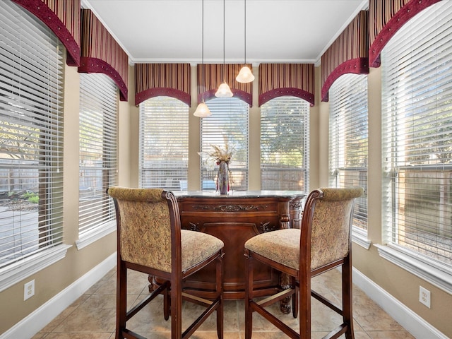 tiled dining room featuring a healthy amount of sunlight, crown molding, and indoor bar