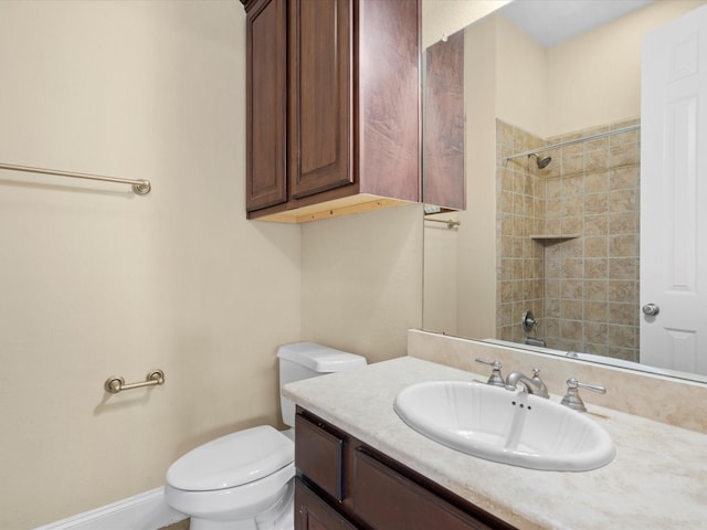 bathroom with toilet, vanity, and tiled shower