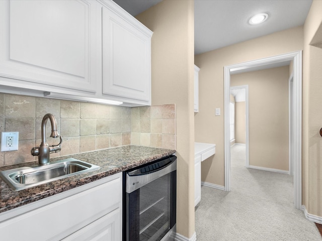 kitchen featuring tasteful backsplash, light carpet, wine cooler, white cabinets, and sink