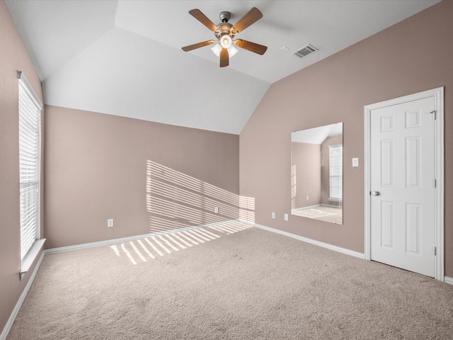 interior space featuring ceiling fan, vaulted ceiling, and carpet