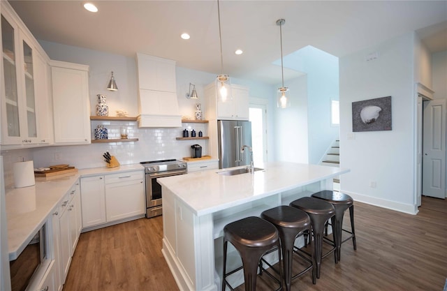 kitchen featuring decorative backsplash, appliances with stainless steel finishes, sink, white cabinetry, and hanging light fixtures