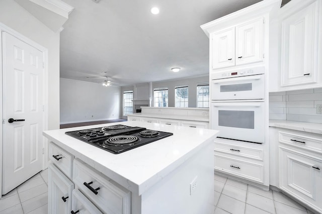 kitchen featuring black electric cooktop, double oven, ceiling fan, light tile patterned floors, and a kitchen island