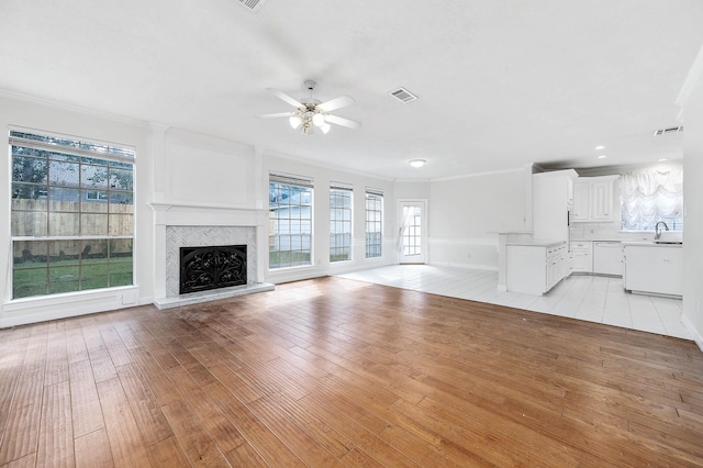 unfurnished living room with ceiling fan, light hardwood / wood-style flooring, crown molding, and sink