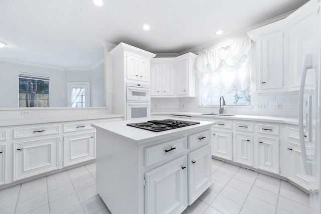 kitchen featuring a center island, white cabinetry, sink, and black stovetop