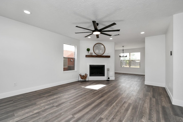 unfurnished living room featuring ceiling fan, dark wood-type flooring, and a textured ceiling