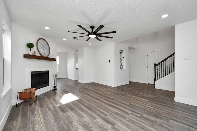 unfurnished living room featuring ceiling fan, dark wood-type flooring, and a textured ceiling