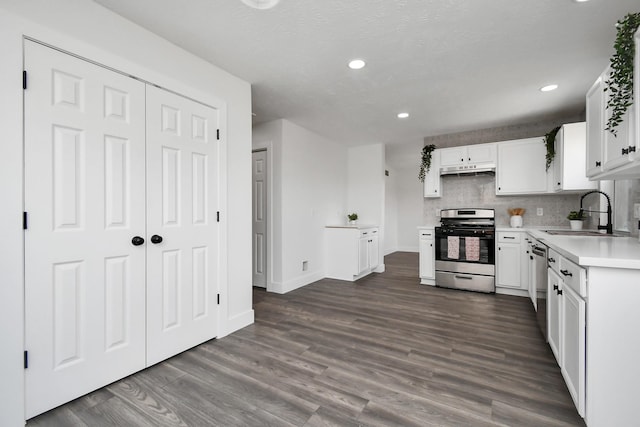 kitchen with dark hardwood / wood-style flooring, backsplash, stainless steel appliances, sink, and white cabinets