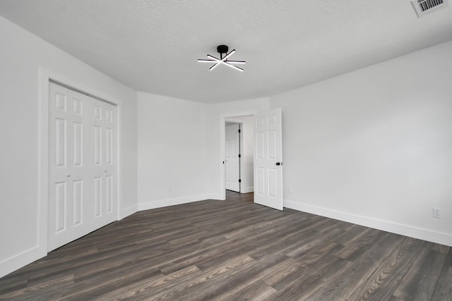 unfurnished bedroom with a textured ceiling, a closet, and dark hardwood / wood-style floors