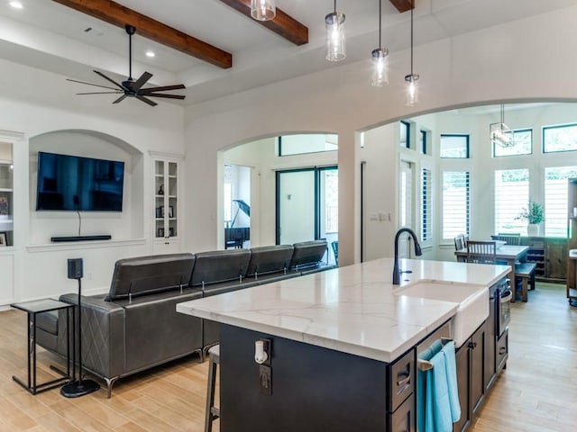 kitchen with a kitchen bar, sink, beamed ceiling, and hanging light fixtures