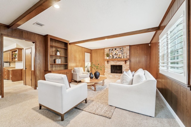 carpeted living room with wooden walls, a fireplace, and beamed ceiling