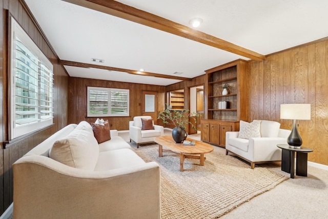 living room with beam ceiling, wood walls, and carpet floors