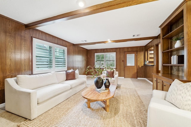 living room featuring beam ceiling, wooden walls, and light colored carpet