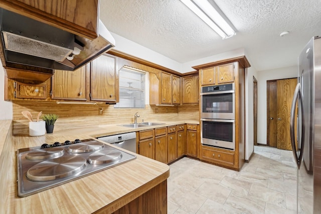 kitchen with backsplash, exhaust hood, sink, a textured ceiling, and stainless steel appliances