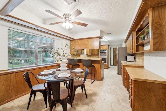 tiled dining room with ceiling fan and a textured ceiling