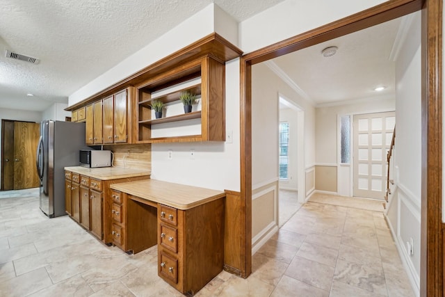 kitchen with tasteful backsplash, stainless steel refrigerator, a textured ceiling, and ornamental molding