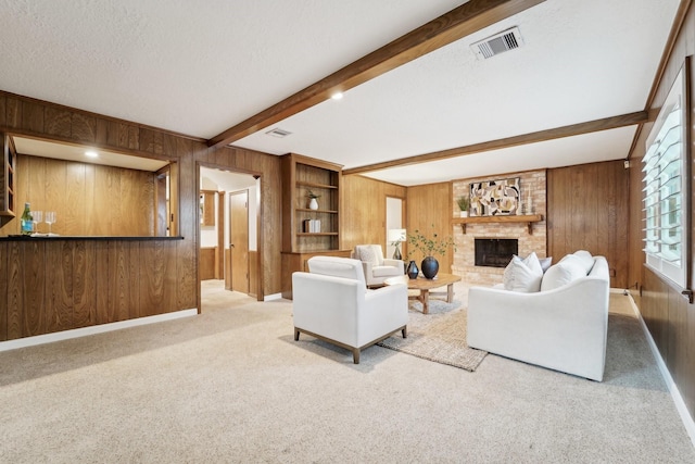 carpeted living room with beam ceiling, built in features, a textured ceiling, and a brick fireplace