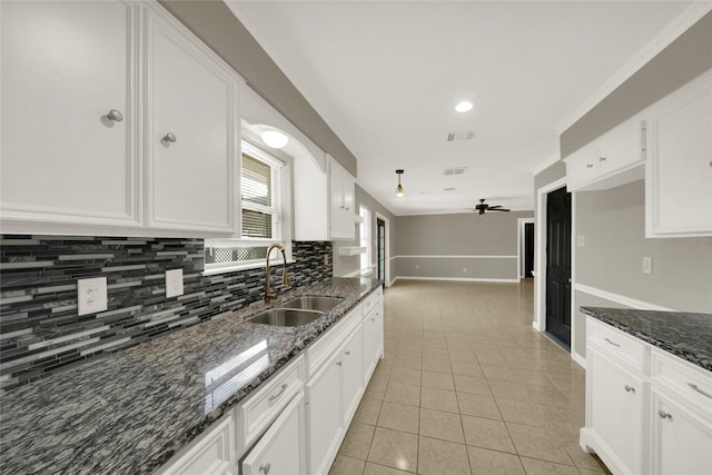 kitchen with white cabinetry, ceiling fan, sink, and dark stone counters