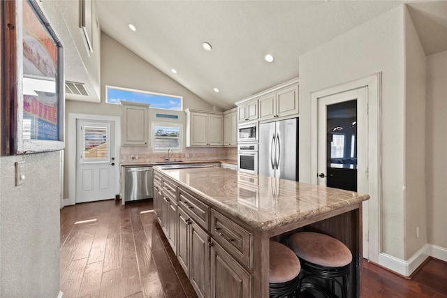 kitchen with built in appliances, light stone countertops, a center island, and dark hardwood / wood-style floors