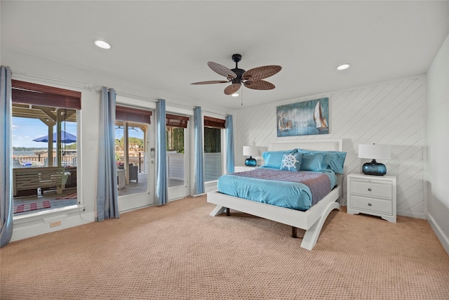 bedroom featuring wooden walls, ceiling fan, light carpet, and access to outside