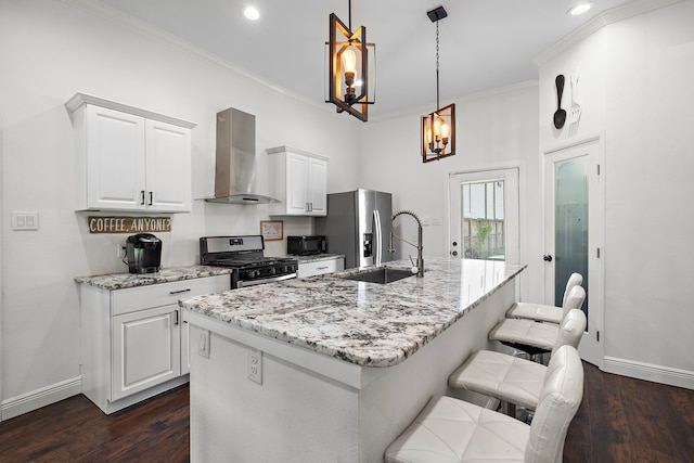 kitchen featuring white cabinetry, hanging light fixtures, stainless steel appliances, and wall chimney range hood