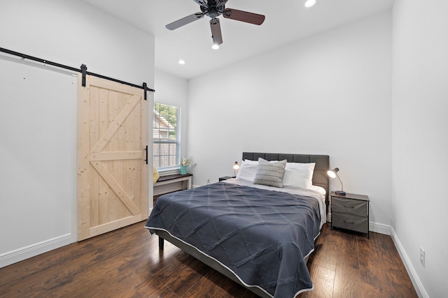 bedroom featuring ceiling fan, a barn door, and dark hardwood / wood-style floors