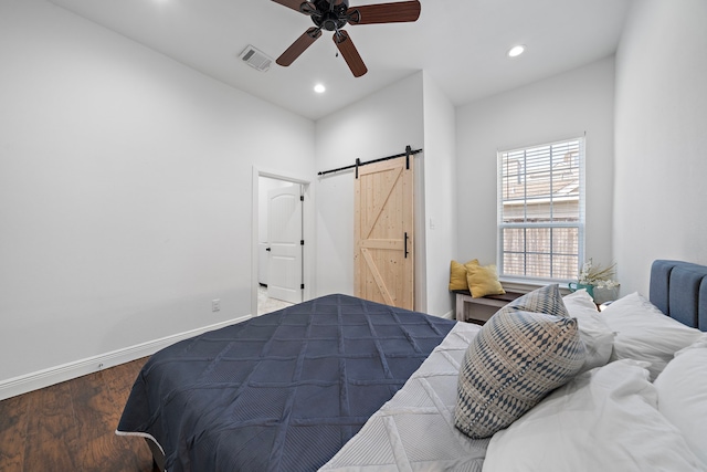 bedroom featuring a barn door, ceiling fan, and wood-type flooring