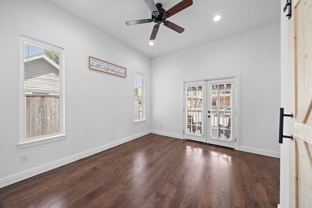 empty room featuring french doors, a barn door, dark hardwood / wood-style floors, and ceiling fan