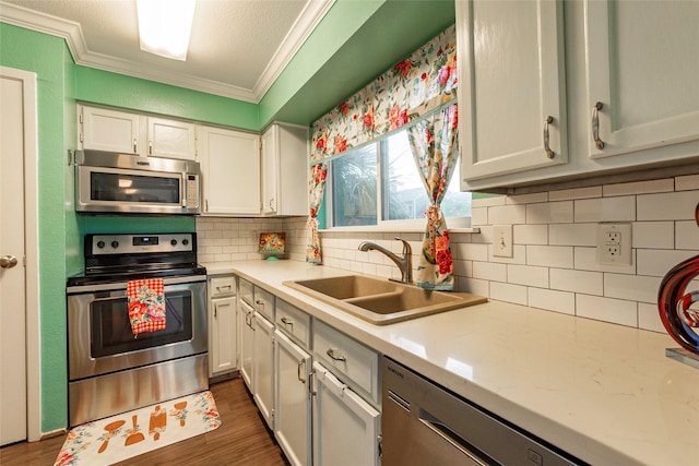 kitchen with white cabinets, crown molding, sink, and appliances with stainless steel finishes