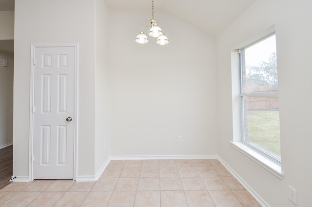 empty room with a healthy amount of sunlight, lofted ceiling, light tile patterned floors, and an inviting chandelier