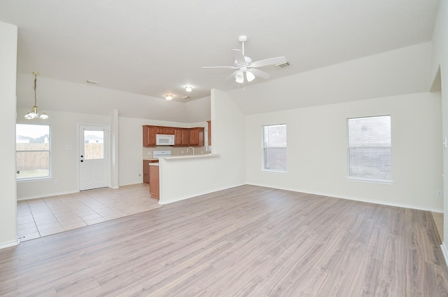 unfurnished living room featuring ceiling fan with notable chandelier, light wood-type flooring, and lofted ceiling