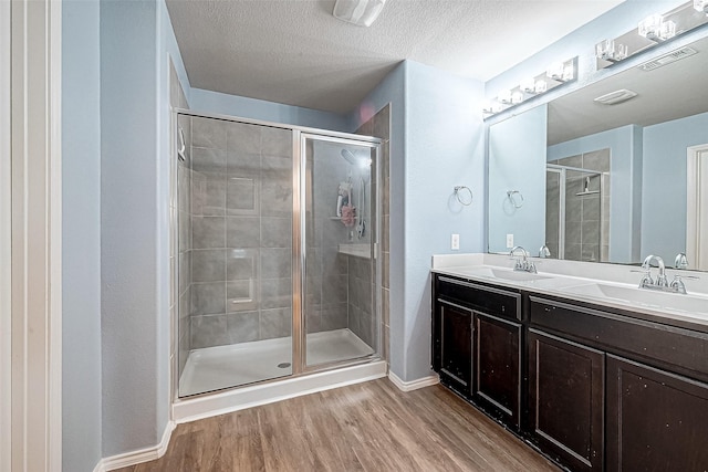 bathroom featuring wood-type flooring, a textured ceiling, and walk in shower