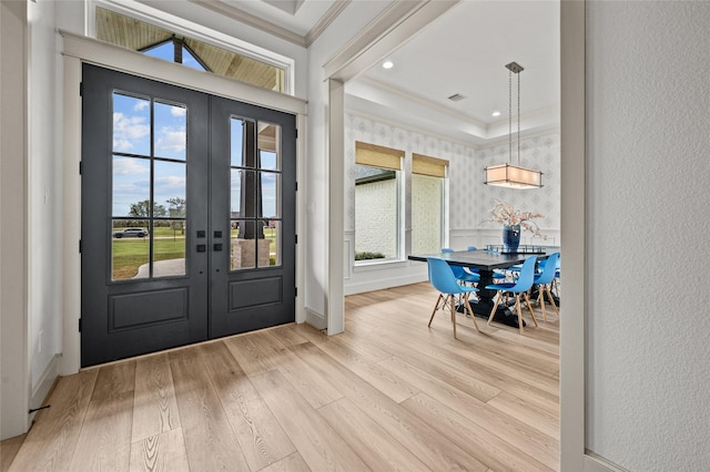 entrance foyer with crown molding, french doors, light wood-type flooring, and a tray ceiling