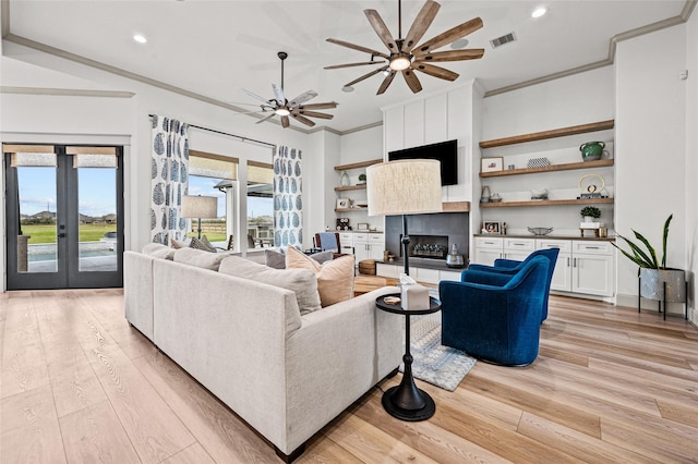 living room with ornamental molding, light wood-type flooring, french doors, and a fireplace