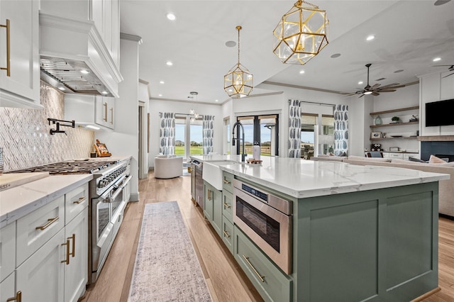 kitchen with custom exhaust hood, pendant lighting, french doors, white cabinetry, and a large island with sink