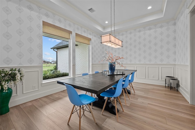 dining space featuring a tray ceiling, crown molding, and light hardwood / wood-style floors