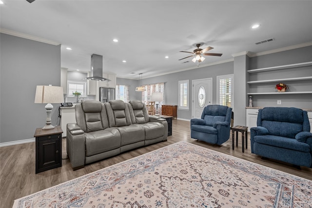 living room featuring hardwood / wood-style flooring, built in features, ceiling fan, and ornamental molding