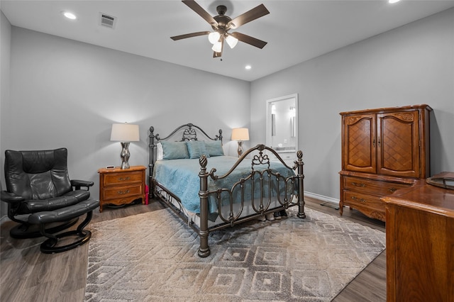 bedroom featuring ceiling fan, ensuite bath, and dark hardwood / wood-style floors