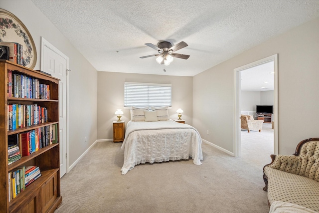 bedroom featuring ceiling fan, light colored carpet, and a textured ceiling