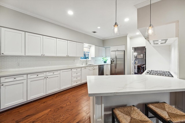 kitchen with white cabinetry, sink, a kitchen breakfast bar, pendant lighting, and appliances with stainless steel finishes