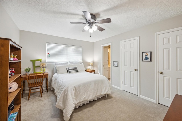 bedroom with a textured ceiling, ceiling fan, light carpet, and ensuite bath